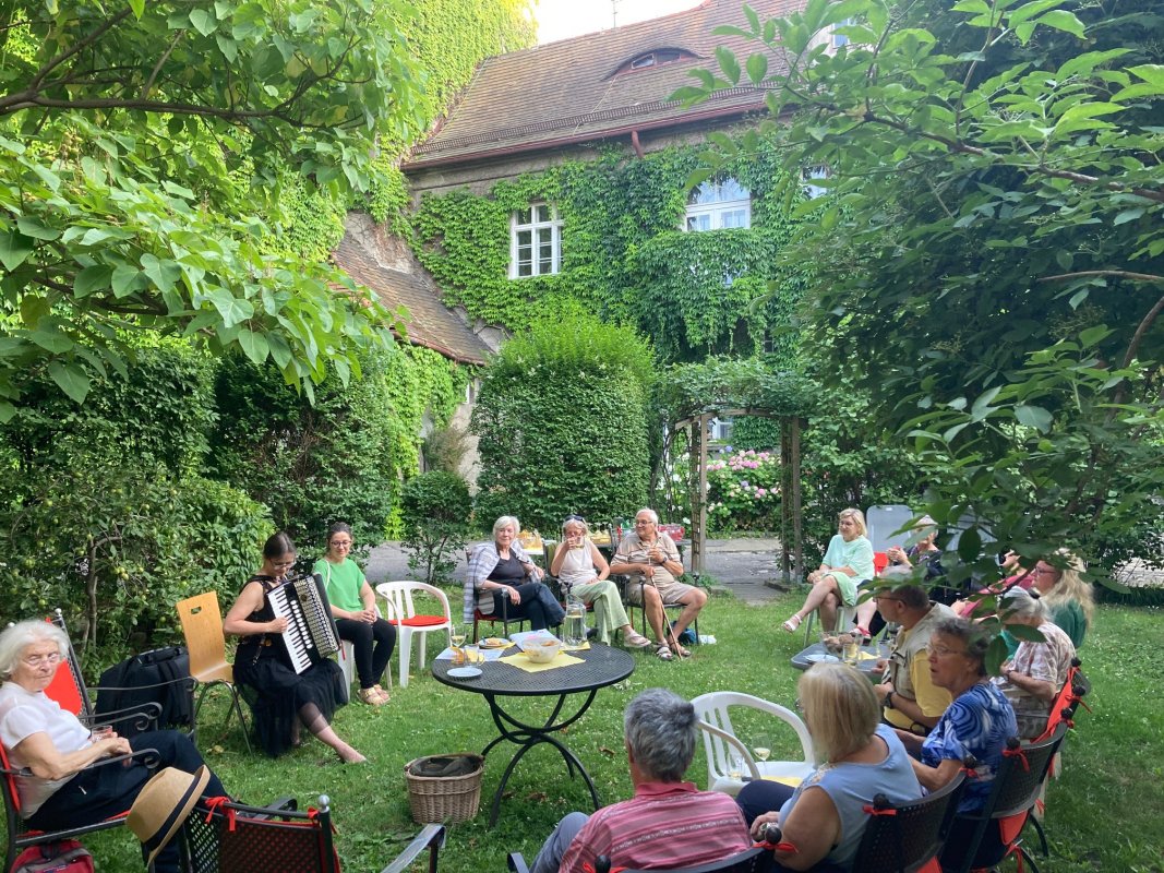 Menschen sitzen im Gartenund singen gemeinsam Menschen sitzen im Gartenund singen gemeinsam